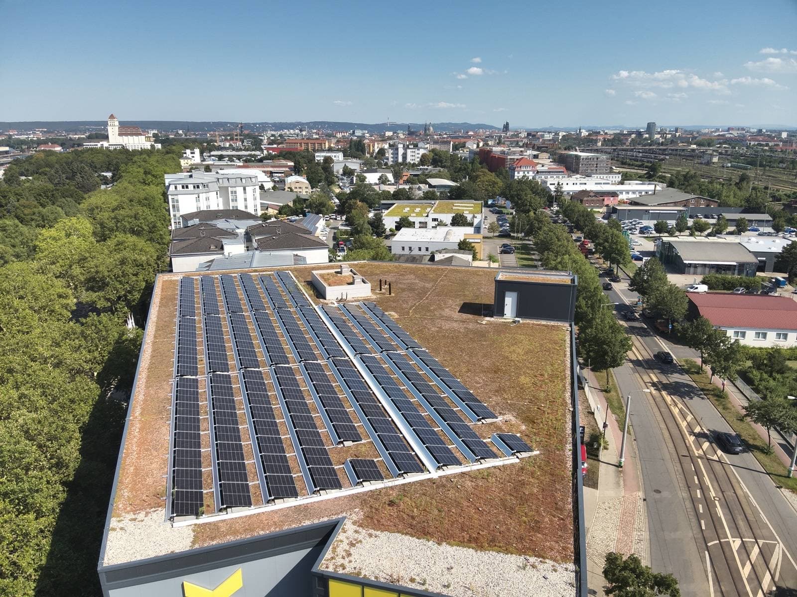 Gründach des Lagergebäudes in Dresden mit Solgate-PV-Anlage, dahinter die Stadtsilhouette
